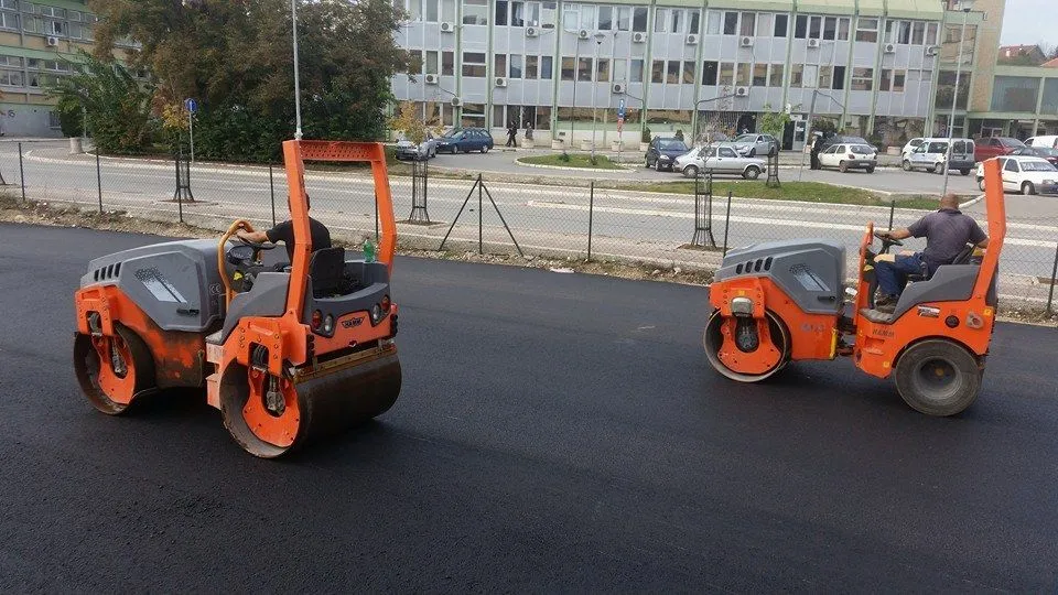 Dva narandžasta tandem valjka zbijaju novi asfalt