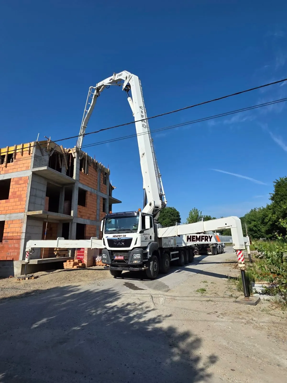 Pumpa za beton Hemfry sa podignutim krakom pored stambenog objekta u izgradnji