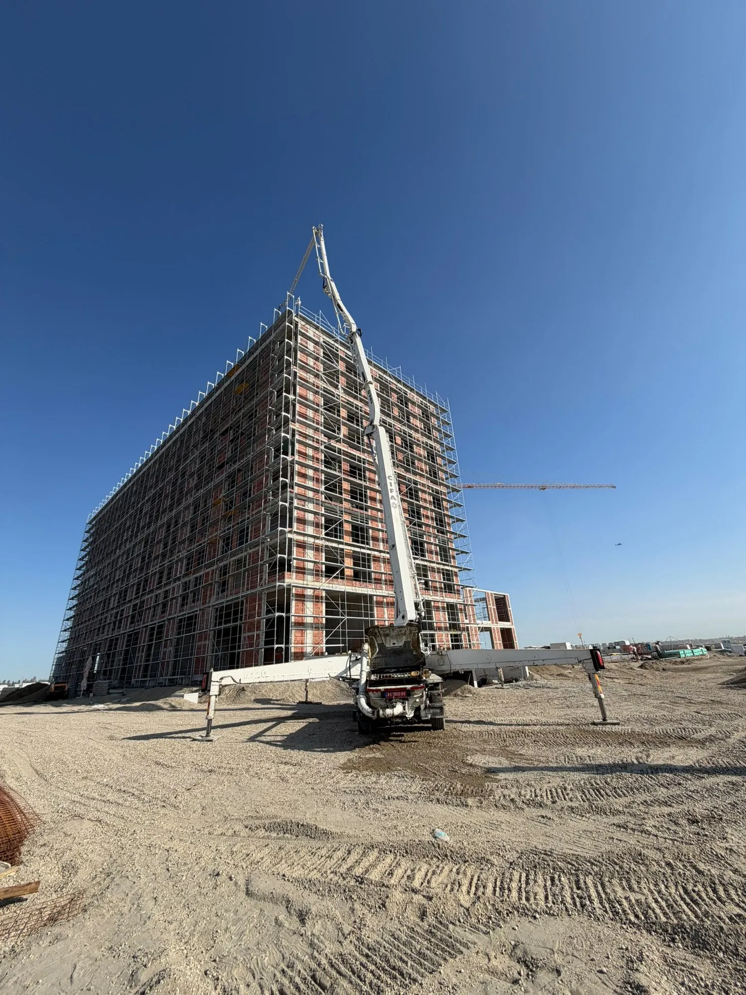 Pumpa za beton sa podignutim krakom pored solitera u izgradnji